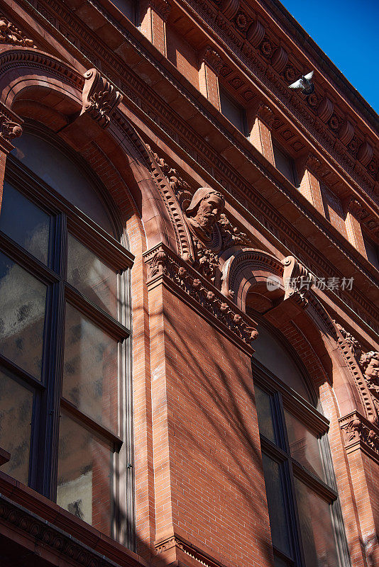 布鲁克林历史协会(Brooklyn Historical Society, 1881年)的红砖和赤土立面，带有拱形窗户、雕塑头像和飞檐，位于纽约市布鲁克林高地。